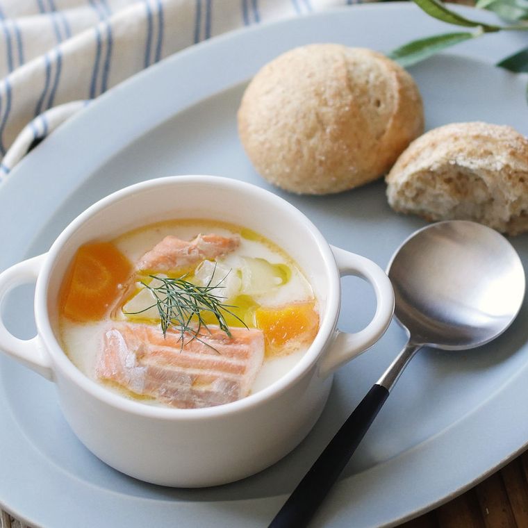 サーモン入りのクリームスープとパンが盛られたオーバル皿