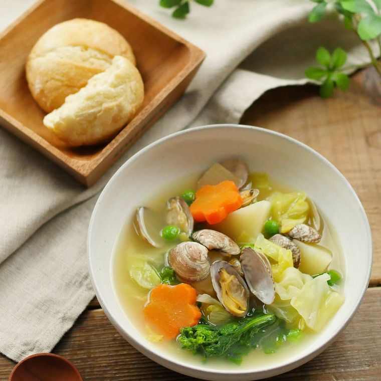 白い器に入っている野菜とあさりのスープ