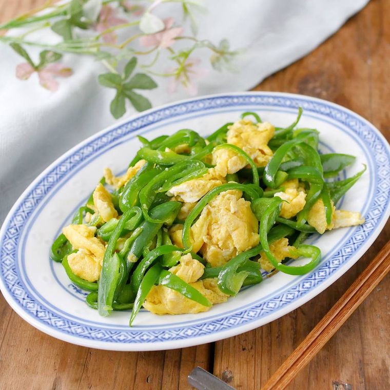 白と青の楕円形のお皿に盛り付けたピーマンと卵の中華炒め