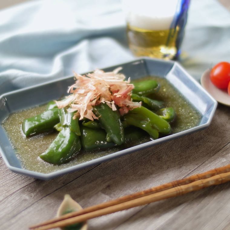 グレーの長方形皿に盛り付けたピーマンのめんつゆバター煮