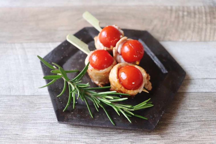 黒いお皿にのったトマトの肉巻き串