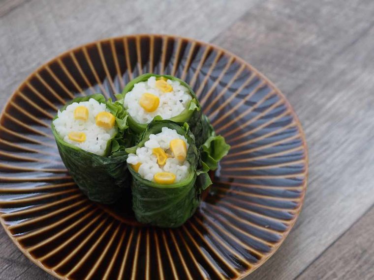 茶色い丸い皿に乗ったレタス巻きコーンおにぎり