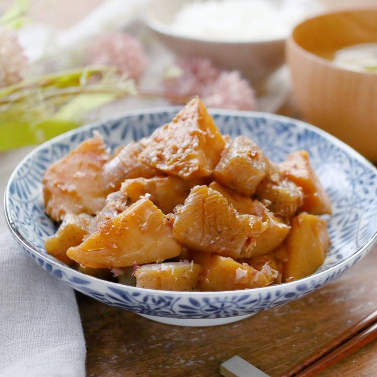 白地に青い模様の入った皿に盛り付けられているたけのことこんにゃくの煮物