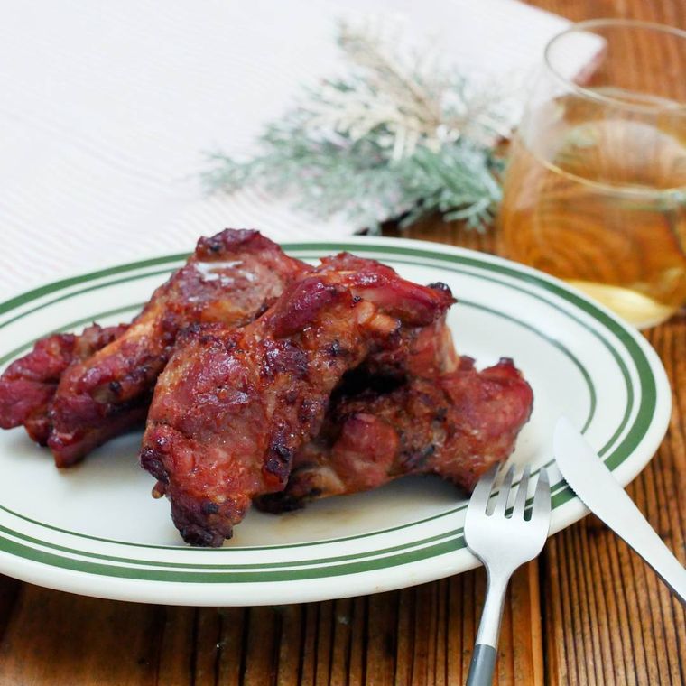 緑色の縁取りの白色の丸皿に盛られたスペアリブのオーブン焼き