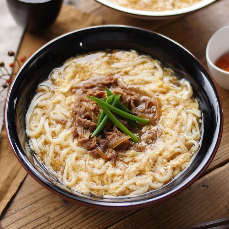 黒い丼茶碗に盛られた肉たまあんかけうどん
