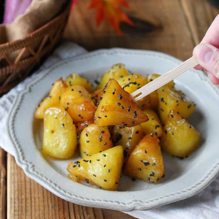 白い皿に盛られた大学いも風さつまいももちを、黒文字で刺して持ち上げている様子