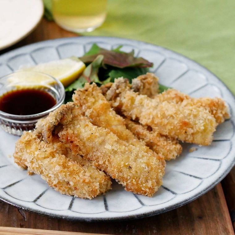 皿に盛りつけられたエリンギフライにレモン、ソース、ベビーリーフが添えられている