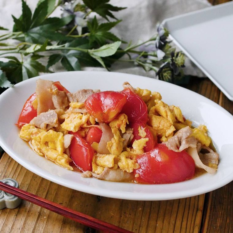 白い皿に盛りつけられた豚肉とトマトの中華風卵炒め