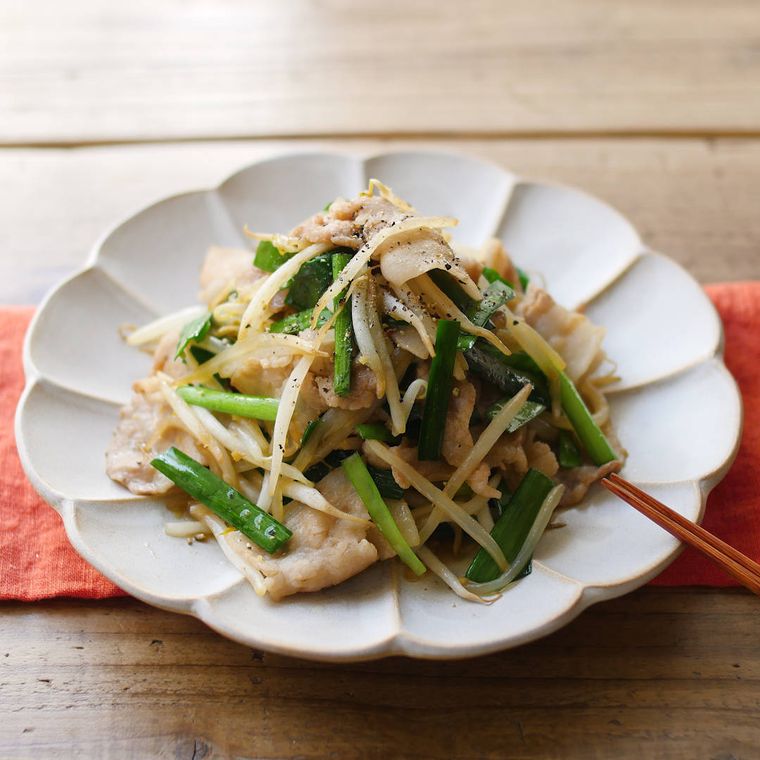 花びら形の白い皿に盛りつけられた豚肉ともやしの炒め物