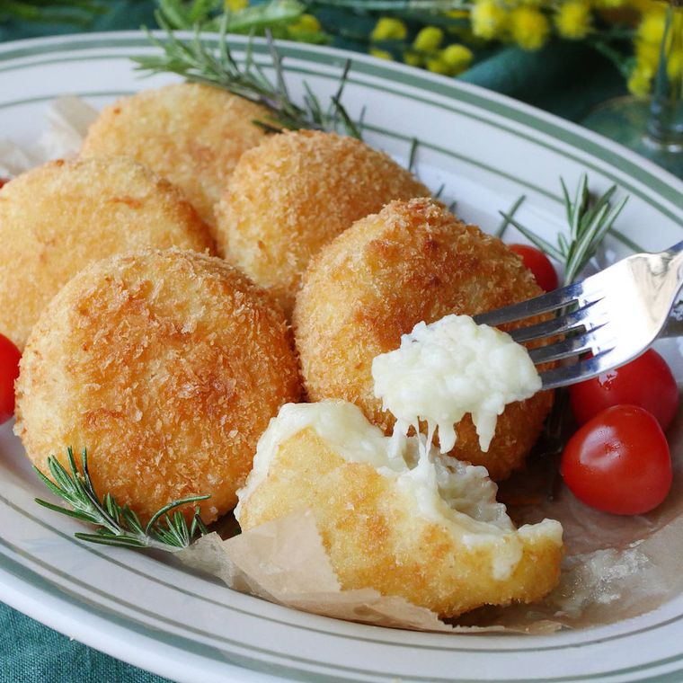 白に緑の線が描かれた皿に盛りつけられたチーズフォンデュコロッケ