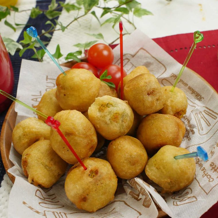 クッキングシートが敷かれた木の皿におかれたさつまいもクリームチーズボール