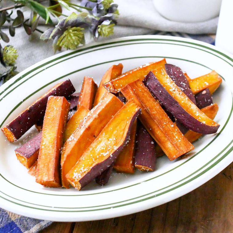 白い楕円形の緑の淵の皿に盛り付けられているさつまいものスティック揚げ