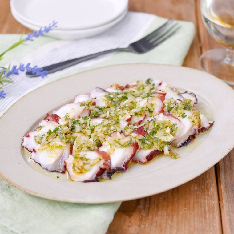 白い楕円形の皿に盛り付けたたこの和風カルパッチョ