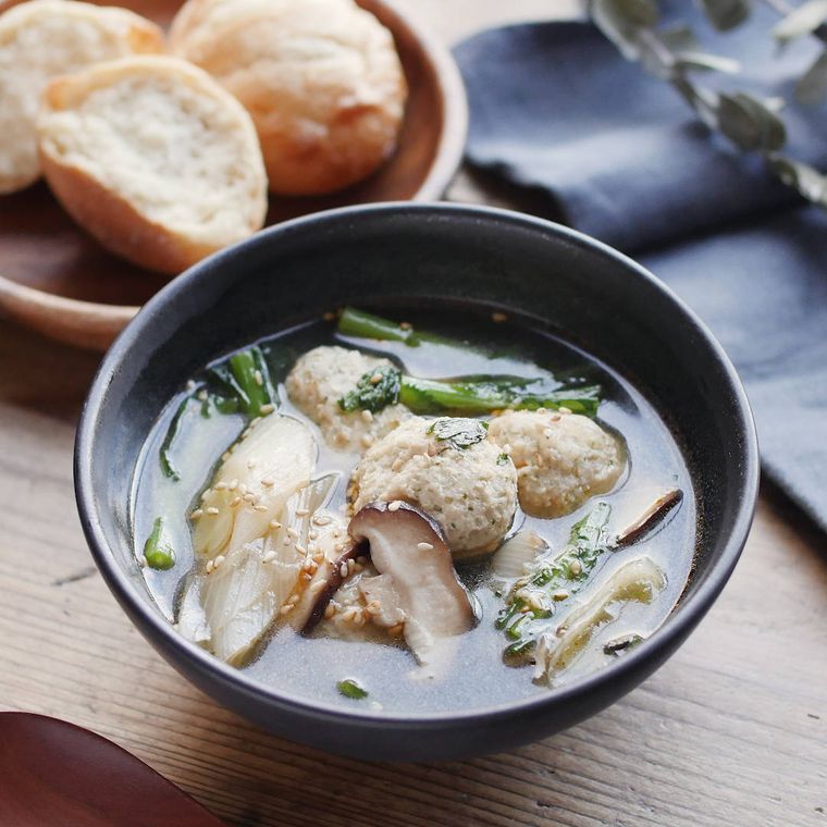 黒い器に盛り付けた春菊と鶏つくねの中華スープ