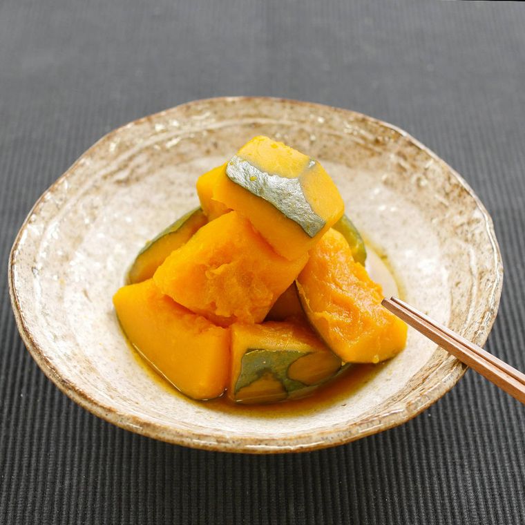 茶色の柄つき皿に盛られたかぼちゃの煮物