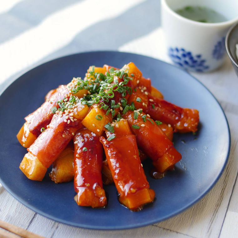 紺色の皿に盛り付けられた餅のピリ辛ベーコン巻き