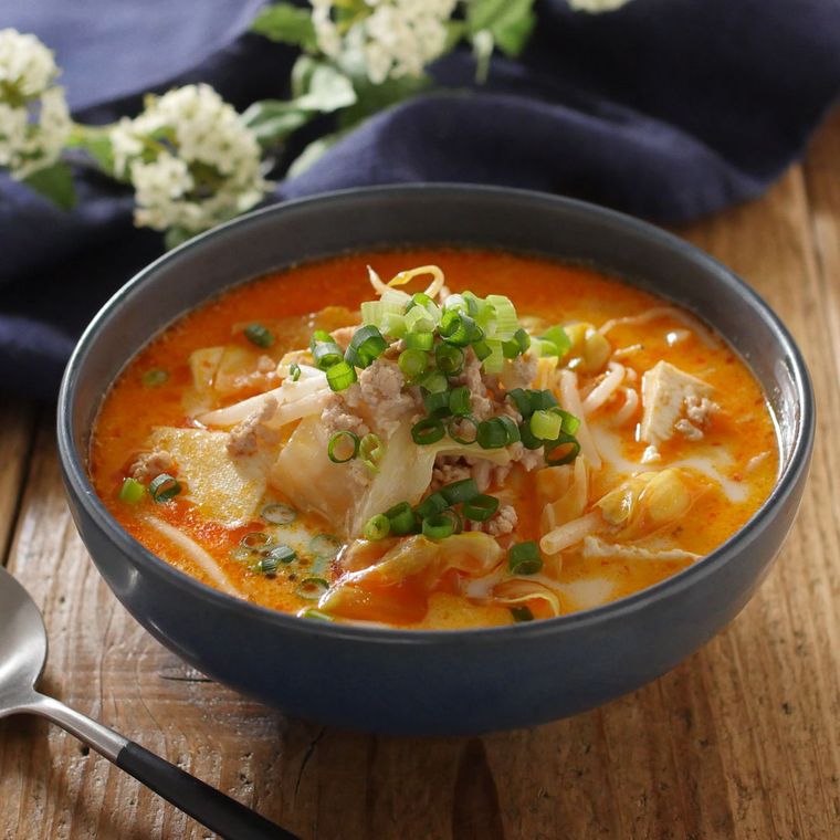 黒いスープ皿に盛り付けされた、豆腐と野菜の豆乳担々スープ