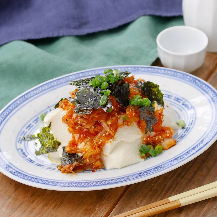 白地に青い模様の楕円形の皿に盛り付けされた、韓国海苔と小口ねぎを振りかけたキムチ豆腐