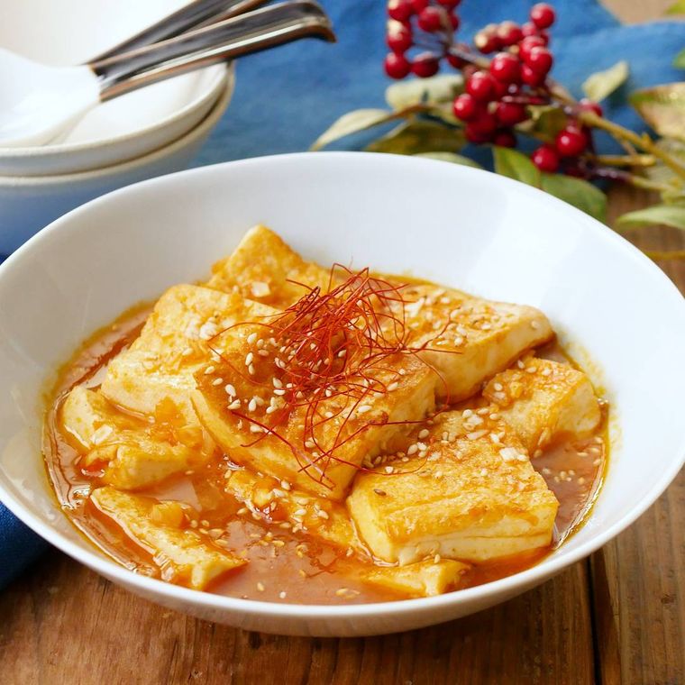 白い深皿に盛り付けられた、豆腐のピリ辛煮込み