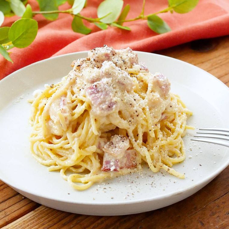 白い丸皿に高く盛り付けされた、ベーコン入りの豆腐カルボナーラ