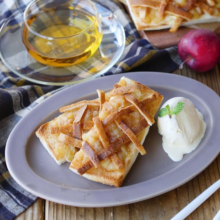 グレーの楕円系のお皿にアップルパイトーストとバニラアイスが盛られ、ガラスのカップにはお茶が入っている