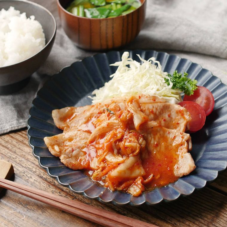 キムチしょうが焼きが黒い皿に盛り付けられているところ