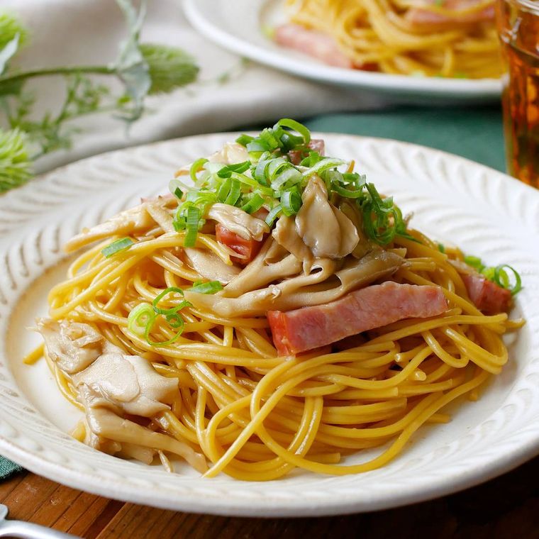 白い丸皿に盛り付けたまいたけとベーコンの和風パスタ