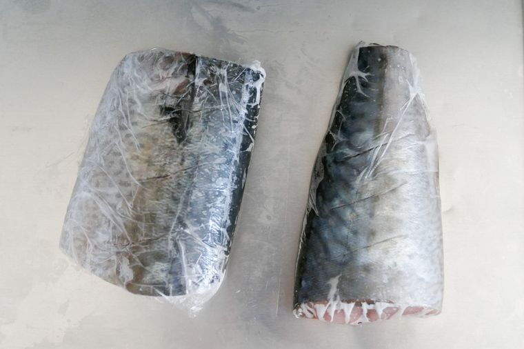 ラップで包んだ冷凍サバを金属トレーにのせて解凍する様子