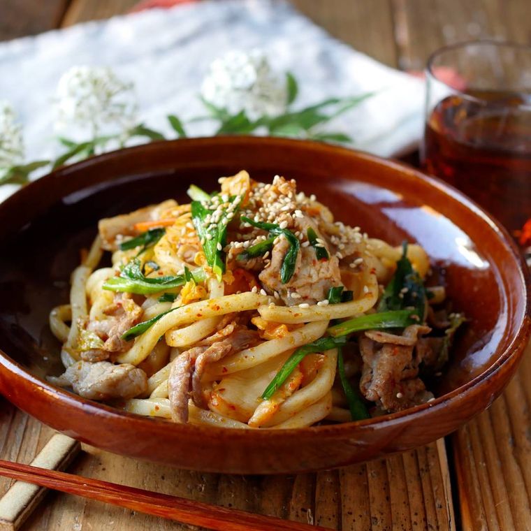 豚キム焼きうどんが茶色い皿に盛り付けられているところ