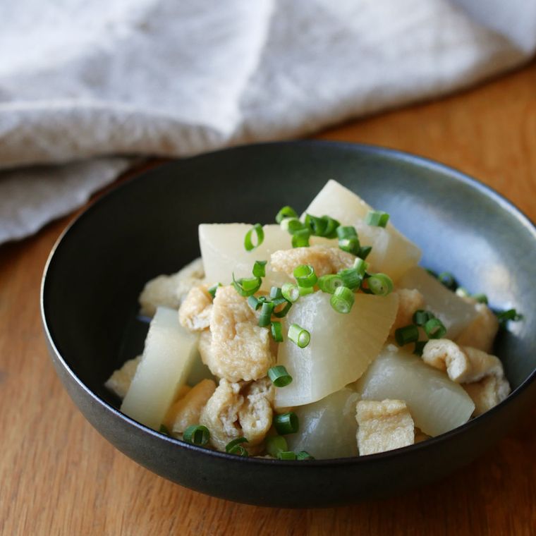 黒い皿に盛られた大根と油揚げの含め煮