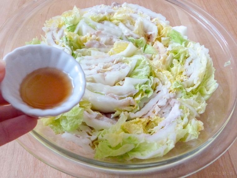 ごま油の入った小皿を持つ手と、白菜と豚肉のミルフィーユ煮が入ったボウル