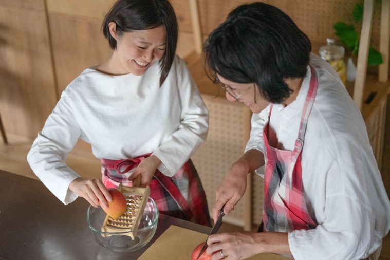 夫婦が一緒に料理をしているシーン。りんごをすりおろしているところと、りんごを切っているところ