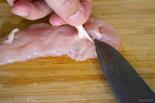 ささみの筋をつかんで包丁の背面で取っている様子