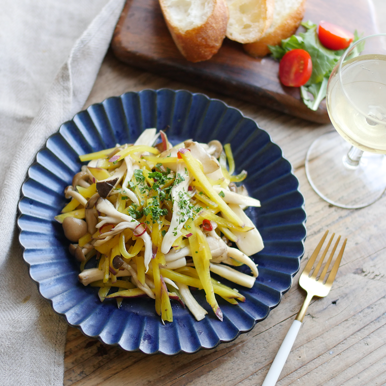 青い皿に盛ったきのことさつまいものガーリック炒め