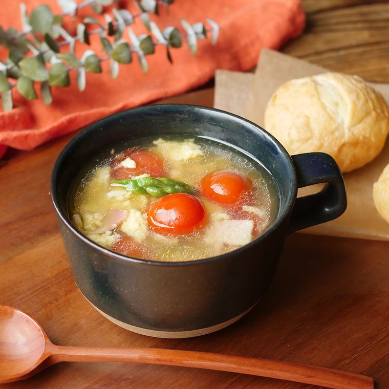 黒いスープカップに盛り付けられたアスパラとミニトマトのスープ