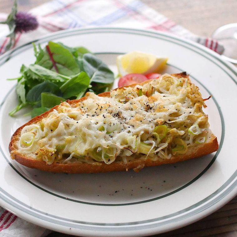 白い皿の上にある長ねぎとしらすのガーリックトーストとリーフサラダ