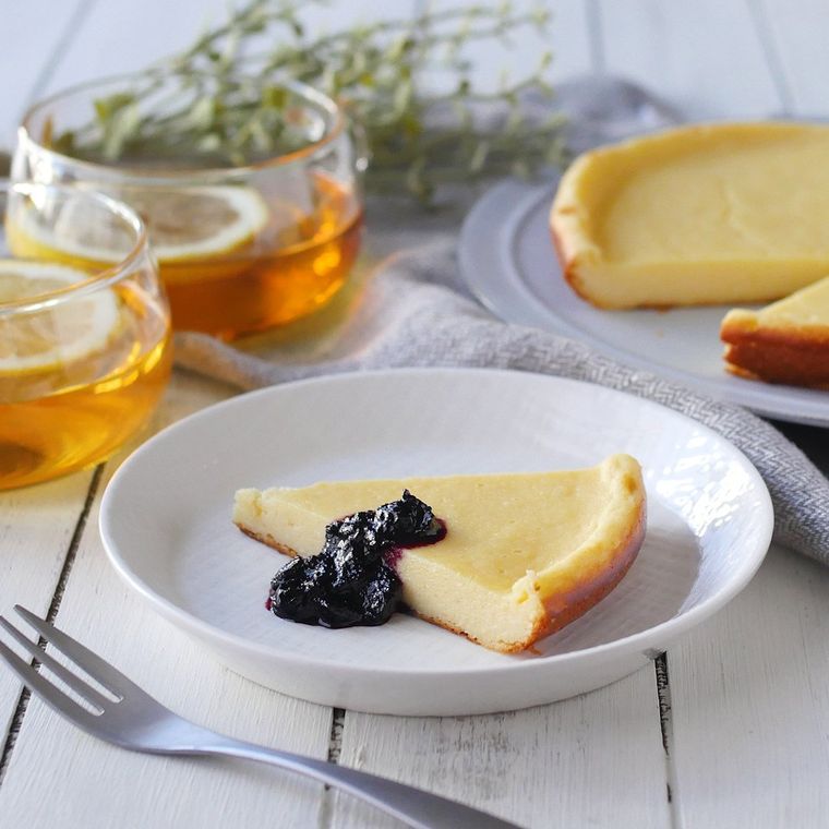 白い皿に盛りつけられたチーズケーキのラズベリージャム添え