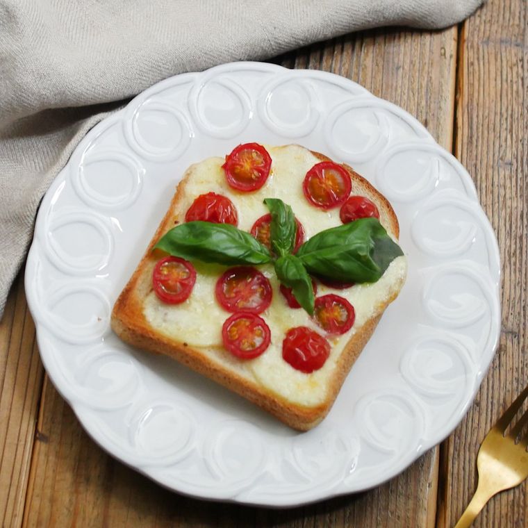 白い皿に盛り付けられたミニトマトのカプレーゼトースト