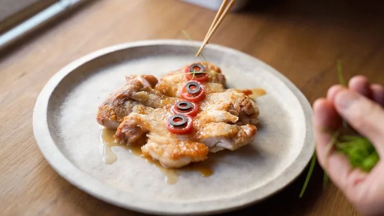 パリパリチキンにミニトマト、黒オリーブ、芽ネギをトッピングしているところ