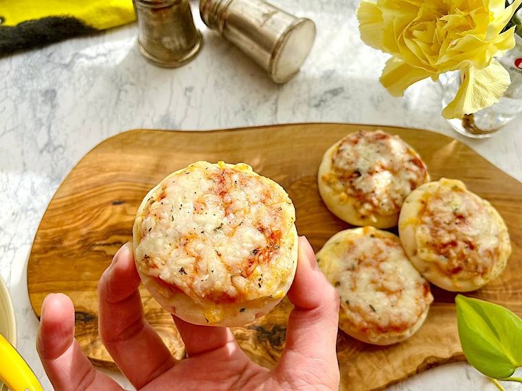 焼いたコストコのミニピザを1枚手に取っているところ