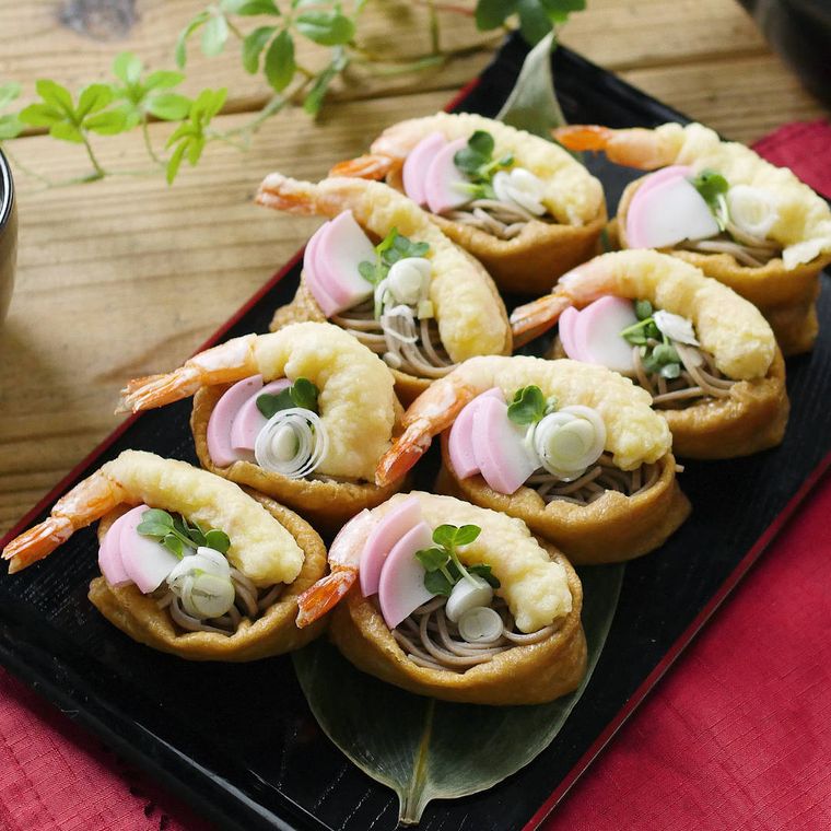 黒い皿に盛られた、天ぷらそばいなり