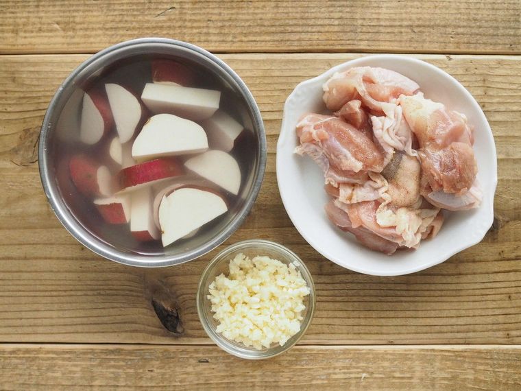 切って水に浸けたさつまいもと皿にのった鶏肉、みじん切りのにんにく