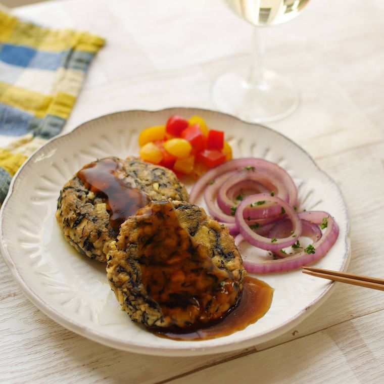 白い丸いプレートに盛り付けられたひじき、たけのこ入りの豆腐ハンバーグ