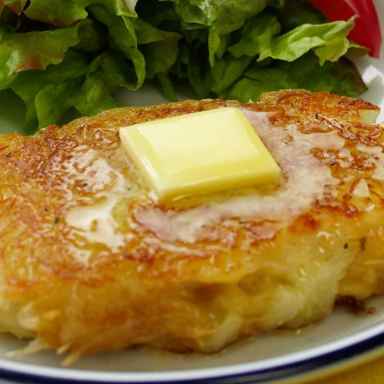 白い丸プレートに盛り付けられたバターののったじゃがいもと鶏ささみのチーズガレット