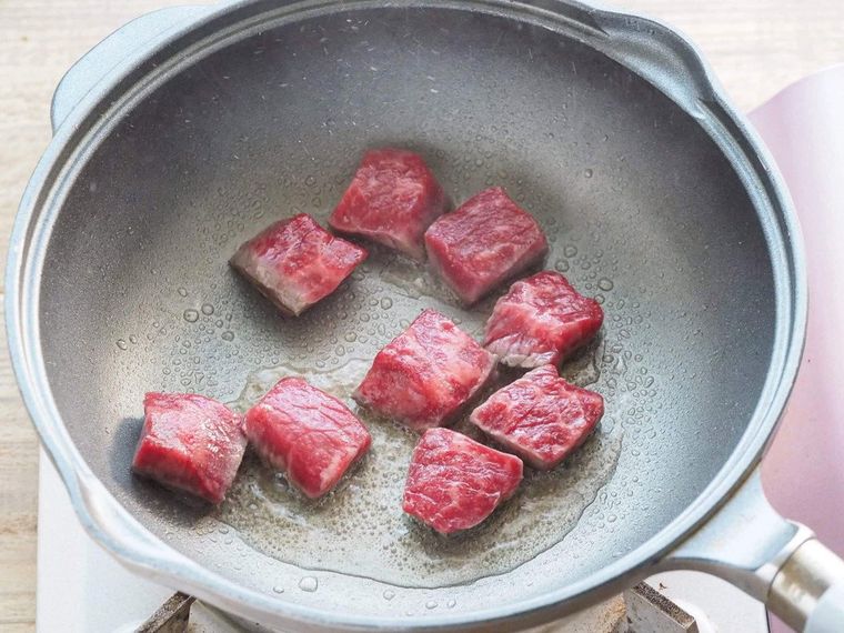 フライパンに入った生に近い角切りの牛肉