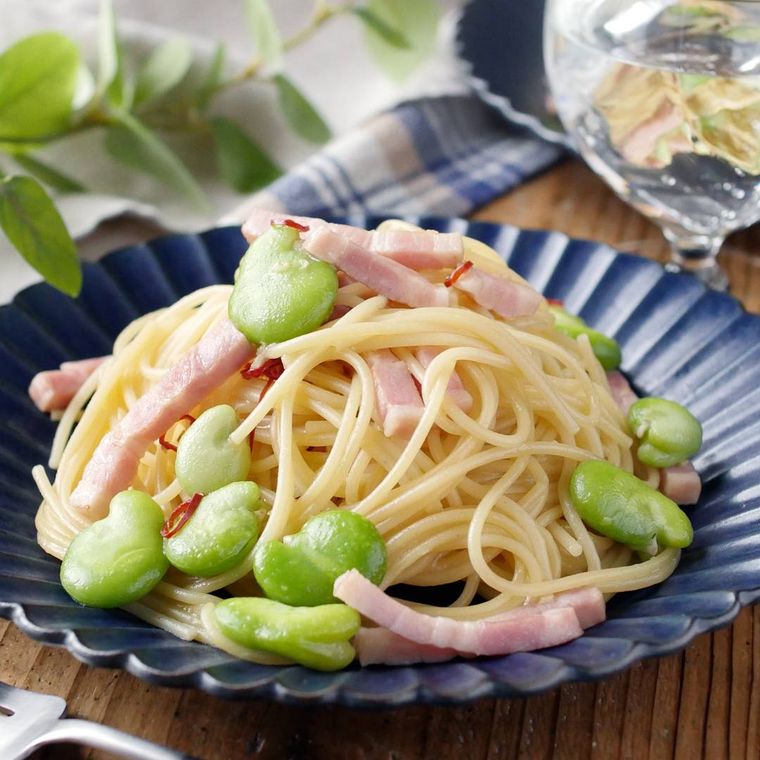 青いパスタ皿に盛られたそら豆とベーコンのペペロンチーノ