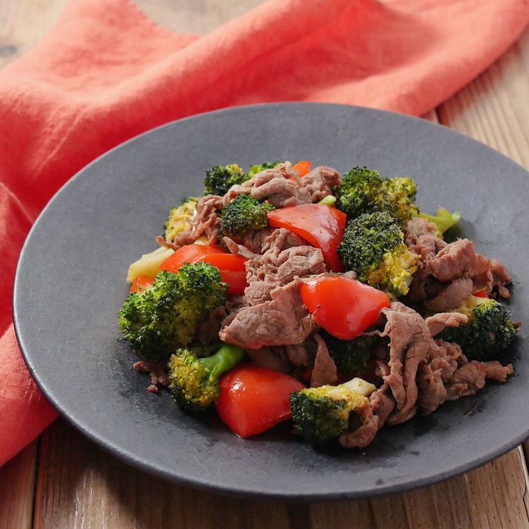 黒い皿に牛肉とブロッコリー、赤パプリカの炒め物がのっている