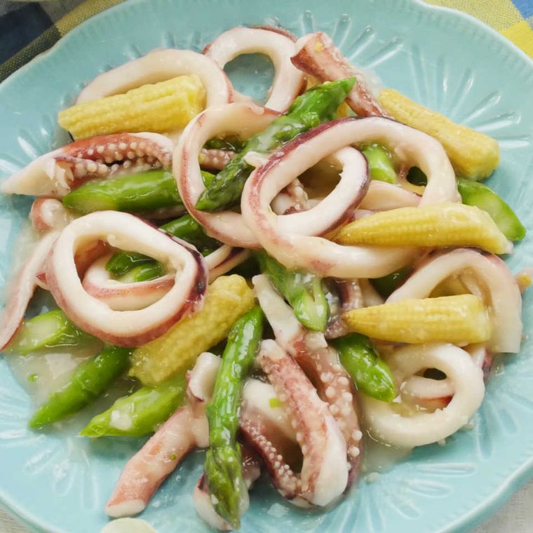 水色の丸プレートに盛り付けられたイカとアスパラのとろりウマ塩中華炒め