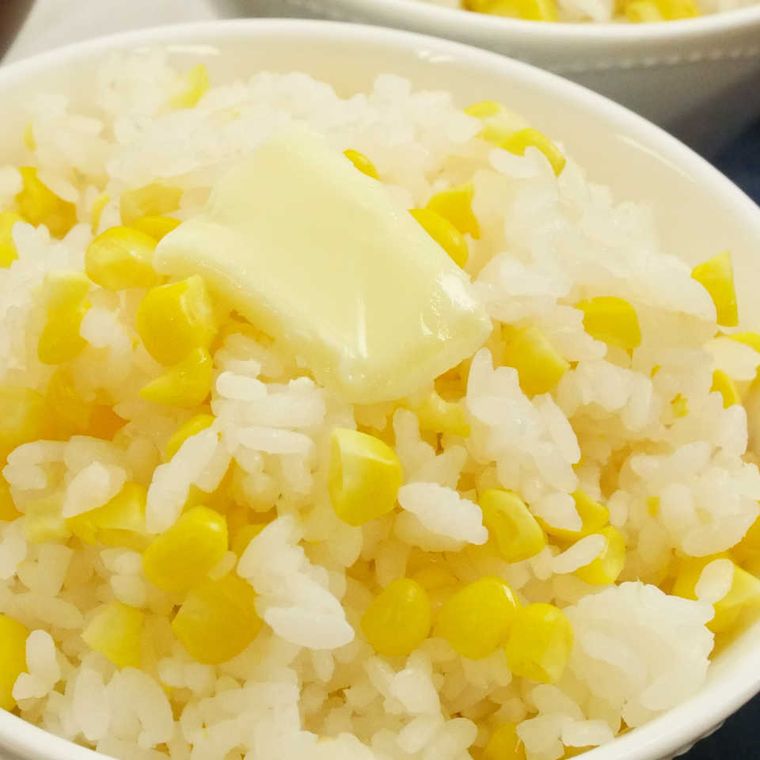 白いご飯茶碗にとうもろこしごはんが盛られていて、バターがひと切れのせられている