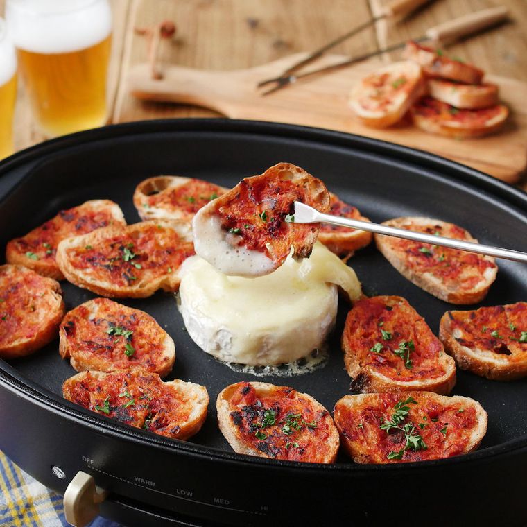 ホットプレートで焼いたバゲットにカマンベールチーズをつけているところ